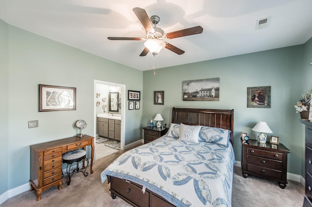 bedroom featuring ceiling fan, light colored carpet, and ensuite bath