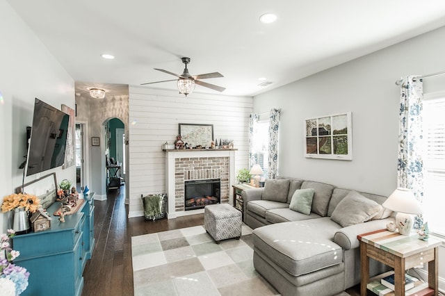 living room featuring a brick fireplace, hardwood / wood-style floors, and ceiling fan