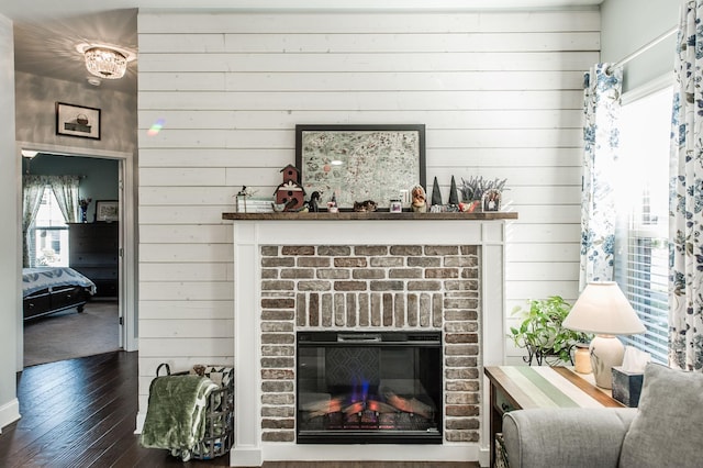 living room with a fireplace, dark hardwood / wood-style flooring, and wood walls