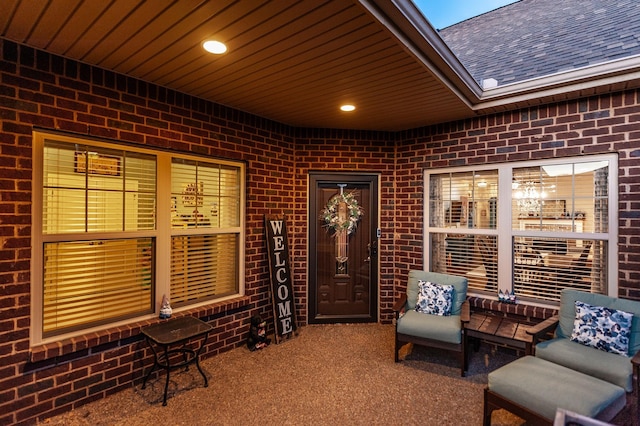 living area with brick wall, carpet, and wood ceiling