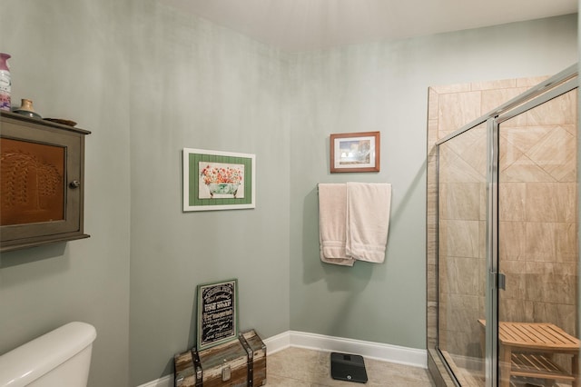 bathroom with tile patterned flooring, a shower with shower door, and toilet