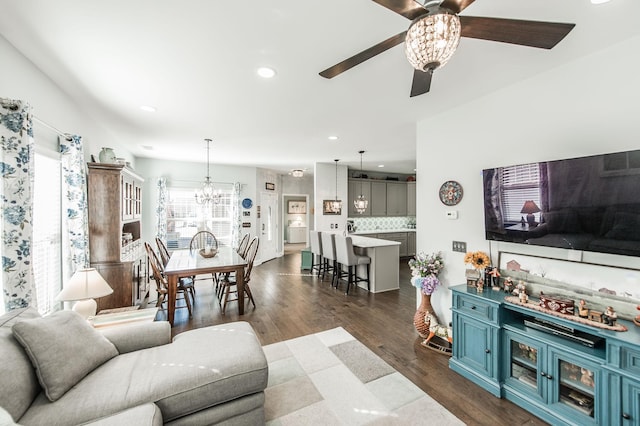 living room with dark hardwood / wood-style flooring, ceiling fan with notable chandelier, plenty of natural light, and washer / dryer