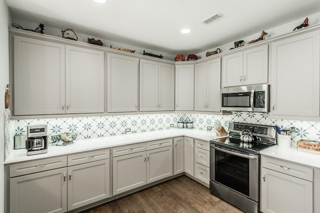 kitchen with backsplash, stainless steel appliances, dark hardwood / wood-style floors, and white cabinets