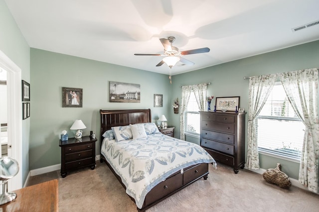 bedroom featuring ceiling fan, multiple windows, and light carpet