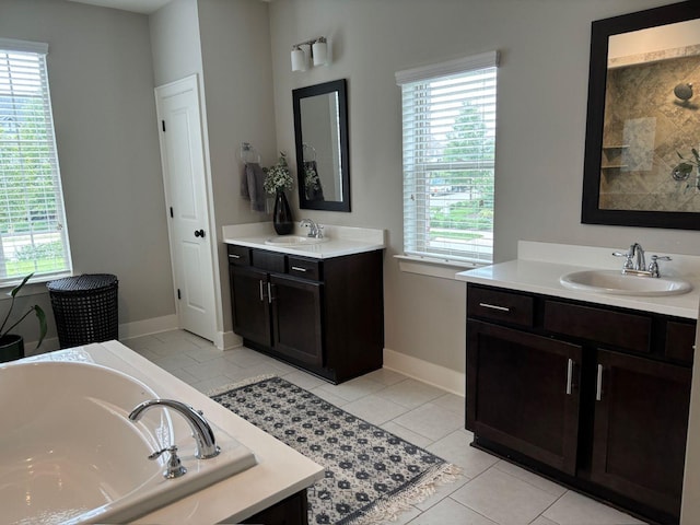 bathroom with tile patterned flooring, vanity, a tub, and a wealth of natural light