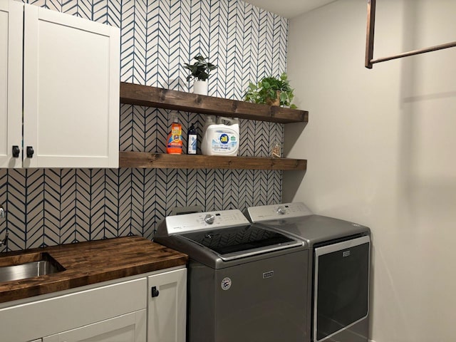 clothes washing area featuring cabinets, washer and dryer, and sink