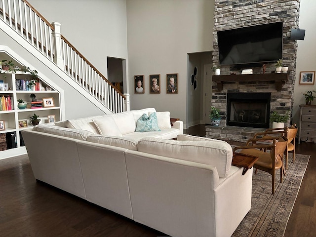 living room featuring dark hardwood / wood-style flooring, a fireplace, and a high ceiling