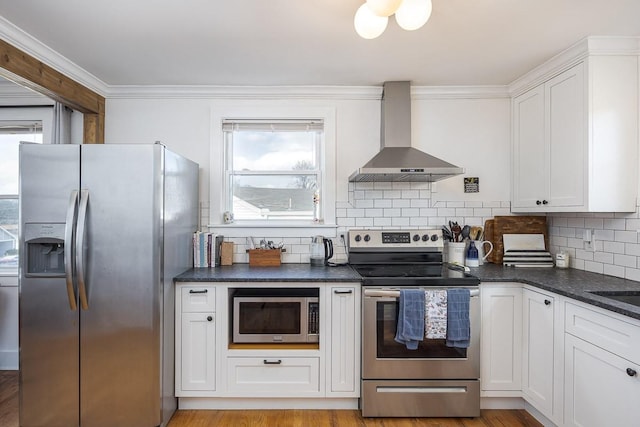 kitchen with white cabinetry, appliances with stainless steel finishes, wall chimney range hood, light hardwood / wood-style floors, and backsplash