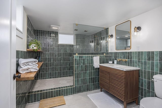 bathroom featuring tile walls, tile patterned flooring, vanity, tiled shower, and toilet