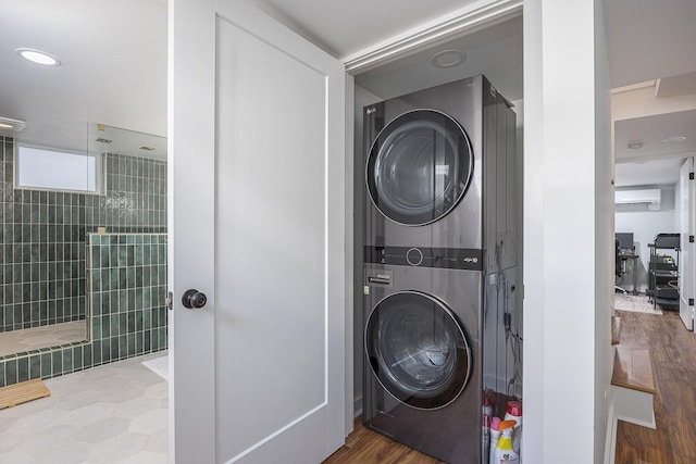 laundry room featuring stacked washer / dryer, hardwood / wood-style floors, and a wall unit AC