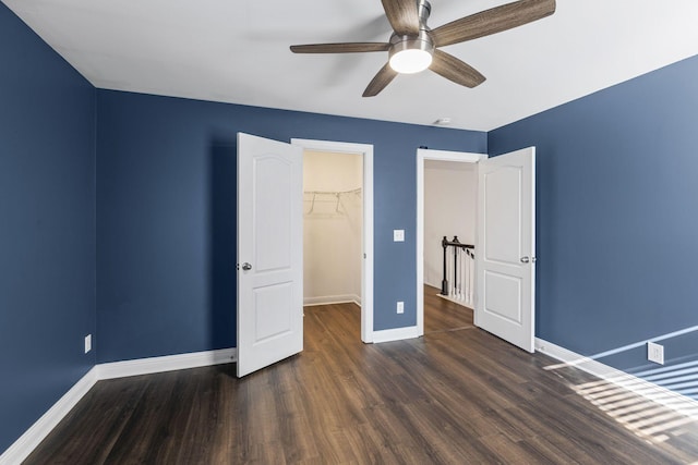 unfurnished bedroom featuring a closet, dark hardwood / wood-style floors, ceiling fan, and a spacious closet