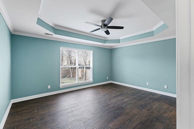 spare room featuring dark hardwood / wood-style flooring, a tray ceiling, ornamental molding, and ceiling fan