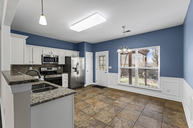 kitchen featuring white cabinetry, hanging light fixtures, backsplash, and appliances with stainless steel finishes