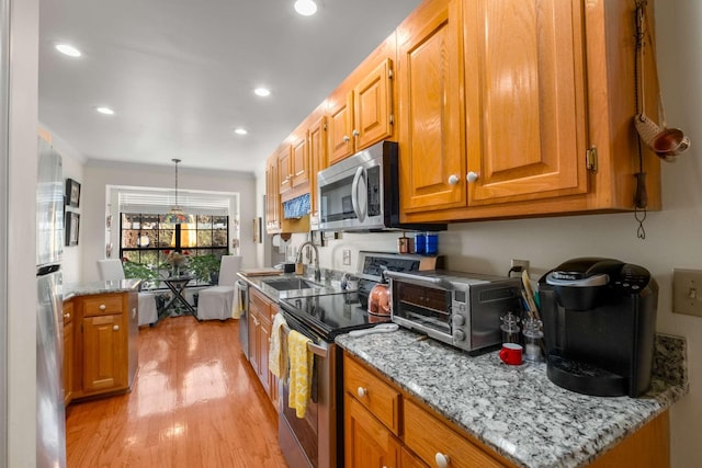 kitchen with appliances with stainless steel finishes, decorative light fixtures, crown molding, light stone countertops, and light wood-type flooring