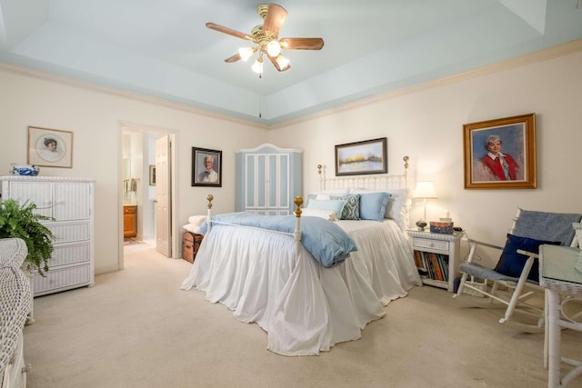 bedroom featuring a tray ceiling, light colored carpet, ceiling fan, and ensuite bathroom