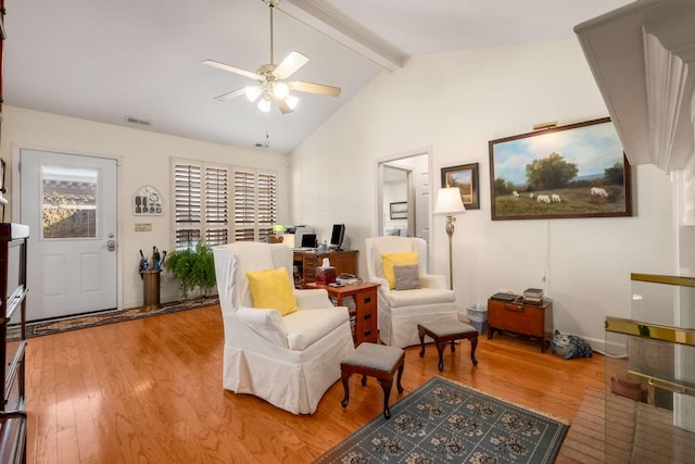 living area with beam ceiling, wood-type flooring, high vaulted ceiling, and ceiling fan