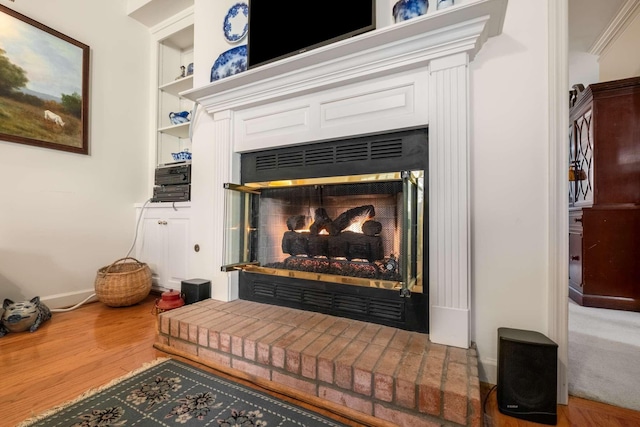 room details with built in features, wood-type flooring, and a brick fireplace