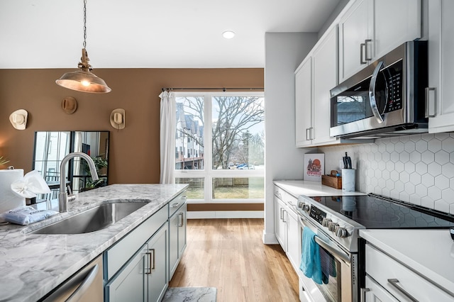 kitchen featuring pendant lighting, white cabinetry, sink, stainless steel appliances, and a healthy amount of sunlight