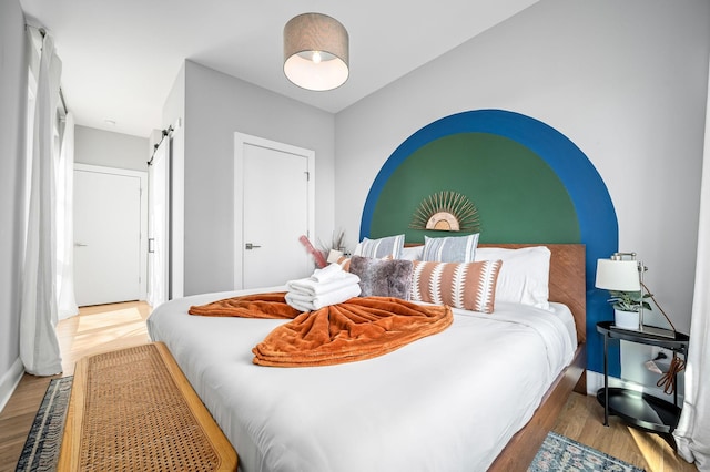 bedroom with wood-type flooring and a barn door