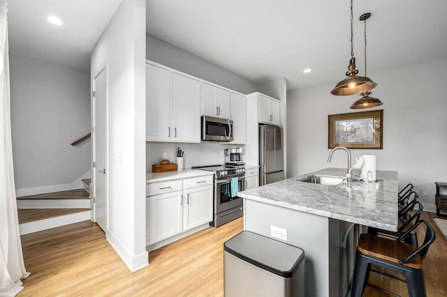 kitchen featuring hanging light fixtures, stainless steel appliances, sink, and white cabinets