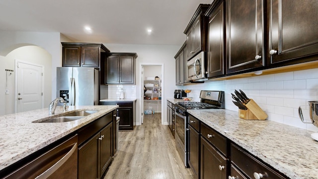 kitchen featuring light stone counters, sink, dark brown cabinets, and appliances with stainless steel finishes