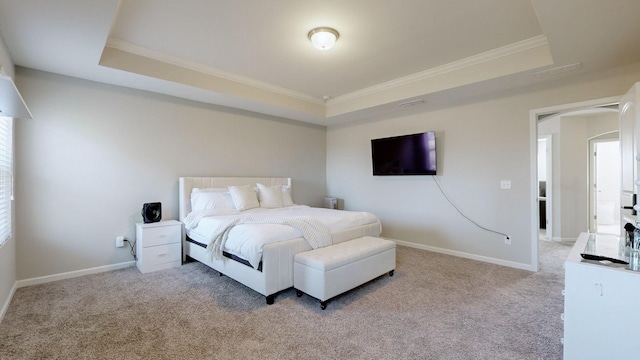 bedroom with crown molding, a tray ceiling, and light carpet