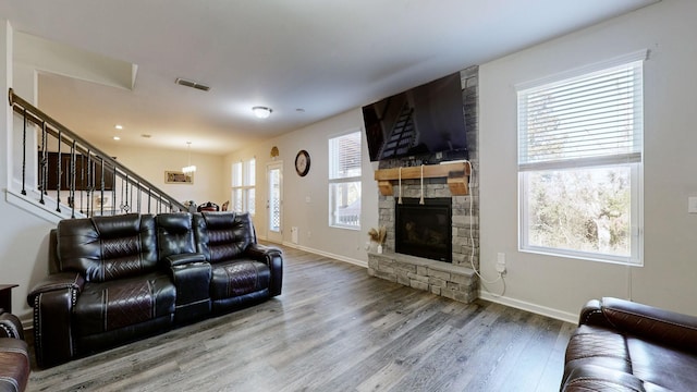 living room with a stone fireplace and hardwood / wood-style floors