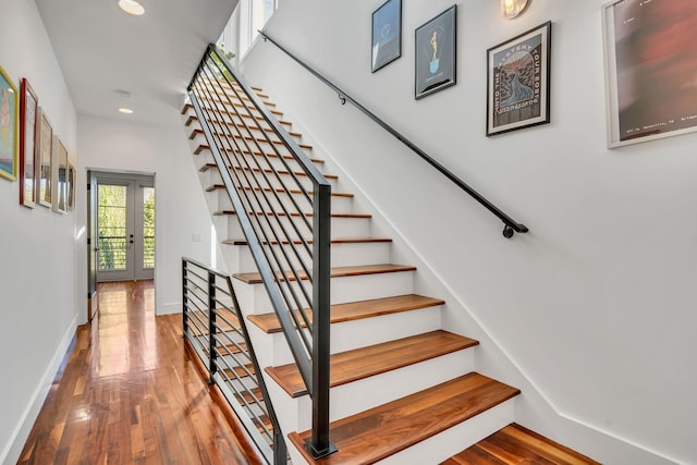 stairs with wood-type flooring and french doors