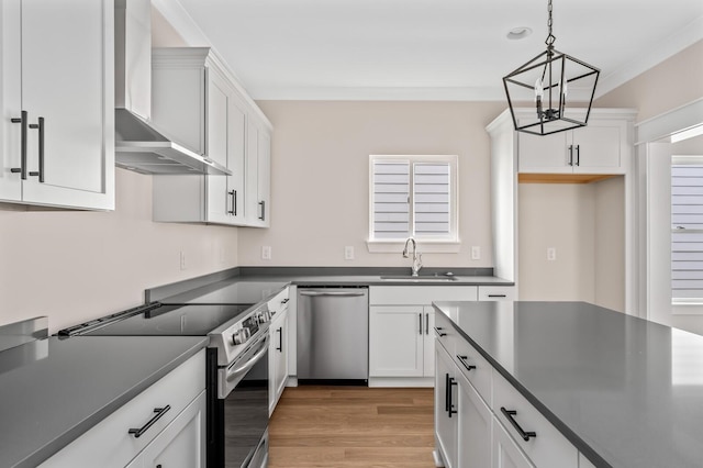 kitchen with sink, white cabinetry, hanging light fixtures, stainless steel appliances, and wall chimney exhaust hood