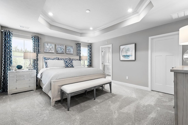 bedroom featuring a raised ceiling, crown molding, carpet, and ensuite bath