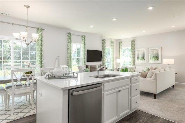 kitchen with decorative light fixtures, sink, white cabinets, stainless steel dishwasher, and a center island with sink