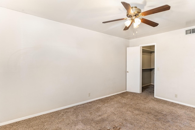 unfurnished bedroom featuring a walk in closet, a closet, ceiling fan, and carpet