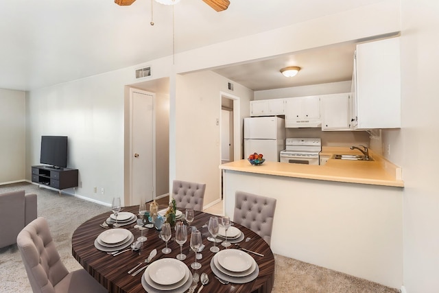 dining space featuring ceiling fan, sink, and light carpet