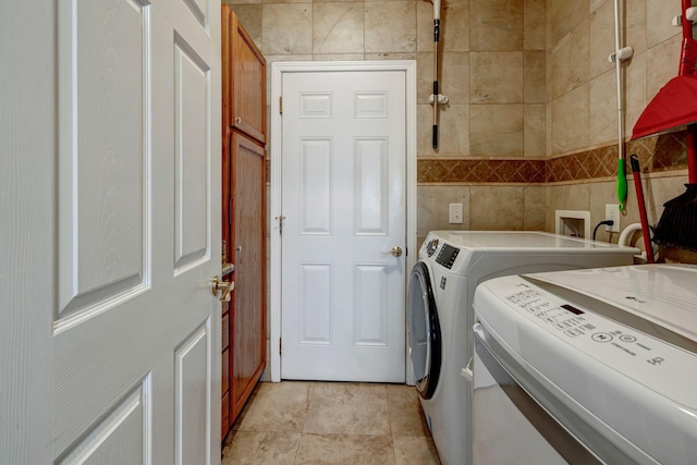 laundry area with separate washer and dryer and tile walls