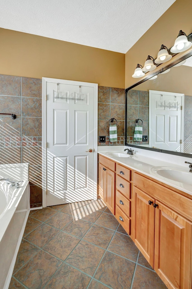 bathroom featuring tile patterned flooring, vanity, a bath, and a textured ceiling