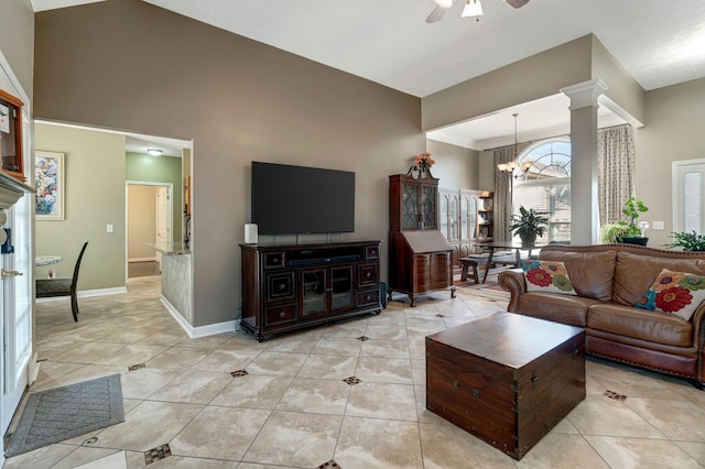 tiled living room featuring ornate columns, ceiling fan with notable chandelier, and high vaulted ceiling