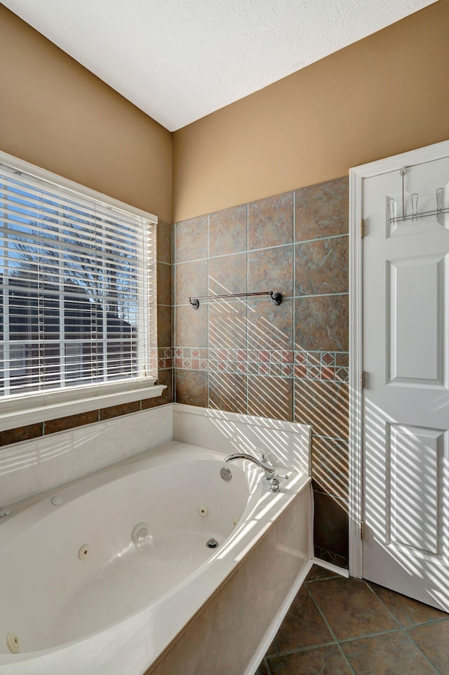 bathroom featuring tile patterned floors, a bathing tub, and a textured ceiling