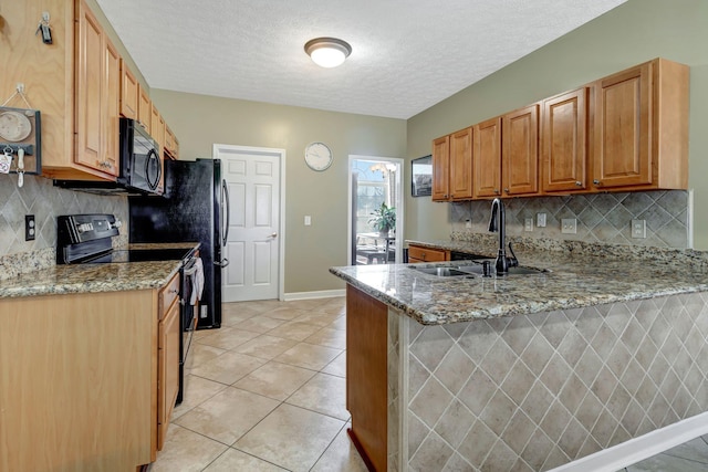 kitchen with sink, light tile patterned floors, light stone counters, black appliances, and kitchen peninsula