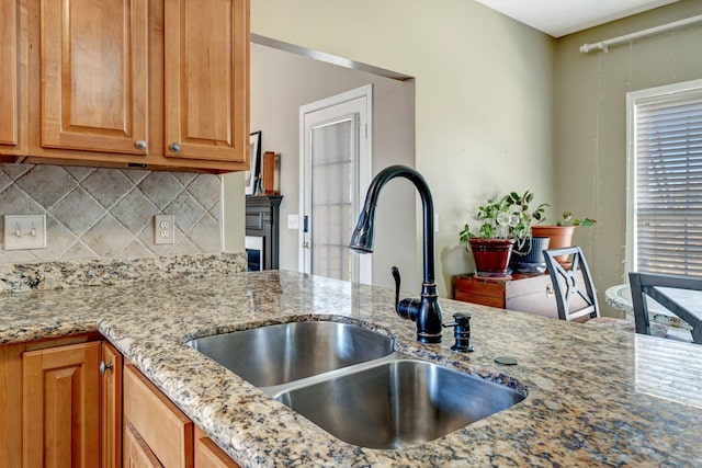 kitchen with light stone countertops, sink, and decorative backsplash