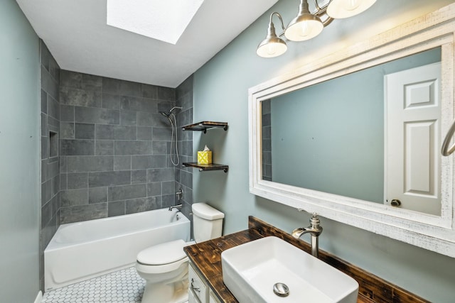 full bathroom with tile patterned flooring, a skylight, vanity, tiled shower / bath, and toilet