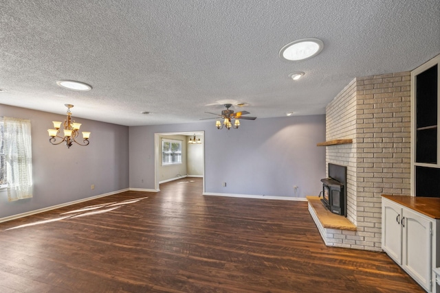 unfurnished living room with a brick fireplace, ceiling fan with notable chandelier, a textured ceiling, and dark hardwood / wood-style flooring