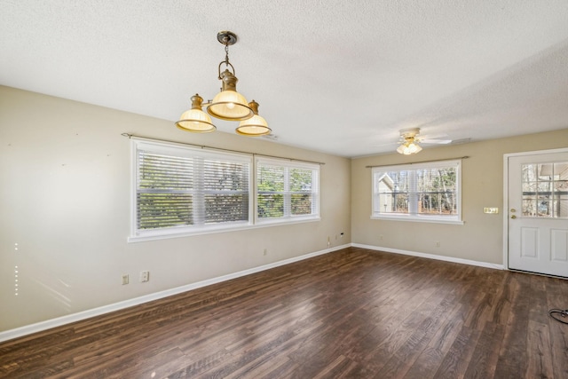 unfurnished room with dark wood-type flooring, ceiling fan with notable chandelier, and a textured ceiling