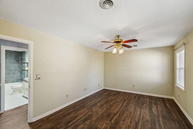 unfurnished room with a textured ceiling, dark wood-type flooring, and ceiling fan