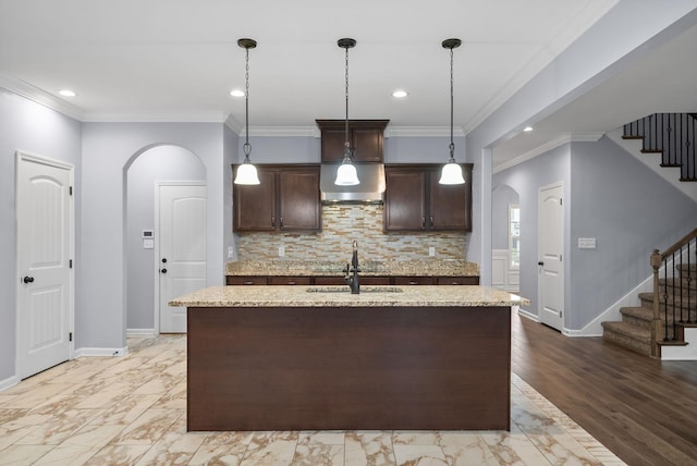 kitchen with sink, hanging light fixtures, dark brown cabinets, and an island with sink