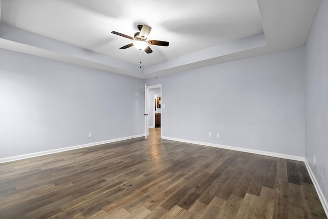 spare room with a raised ceiling, dark hardwood / wood-style floors, and ceiling fan