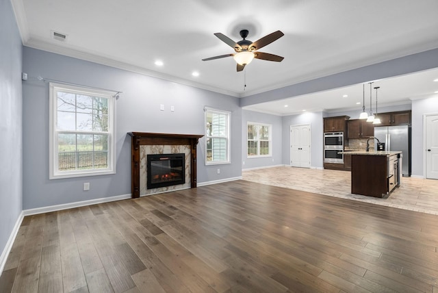 unfurnished living room with crown molding, a fireplace, light hardwood / wood-style floors, and ceiling fan