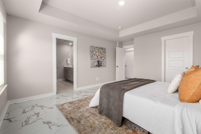 bedroom with ensuite bathroom and a tray ceiling