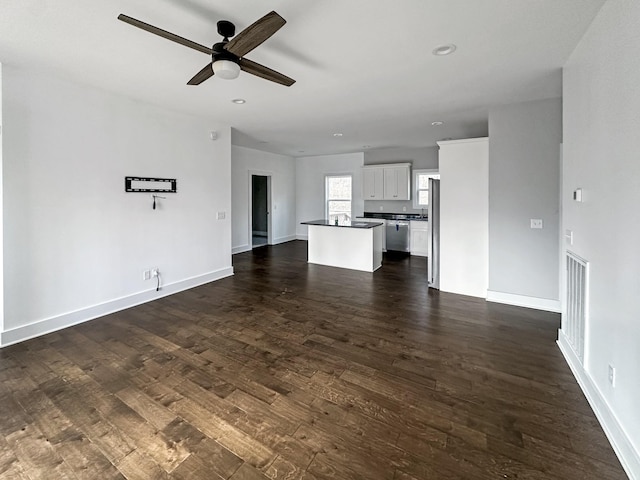 unfurnished living room featuring dark wood-type flooring and ceiling fan