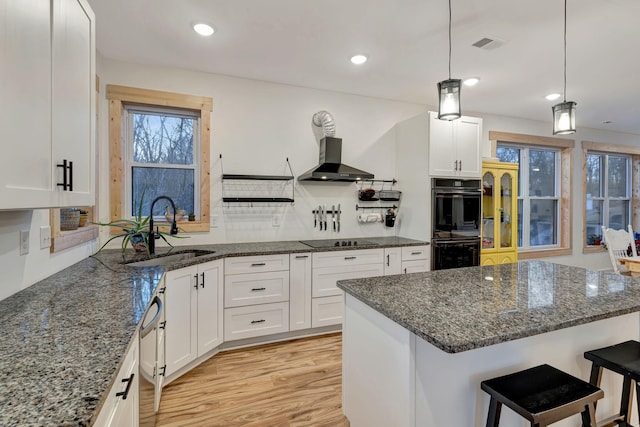 kitchen with white cabinetry, sink, decorative light fixtures, and a kitchen bar