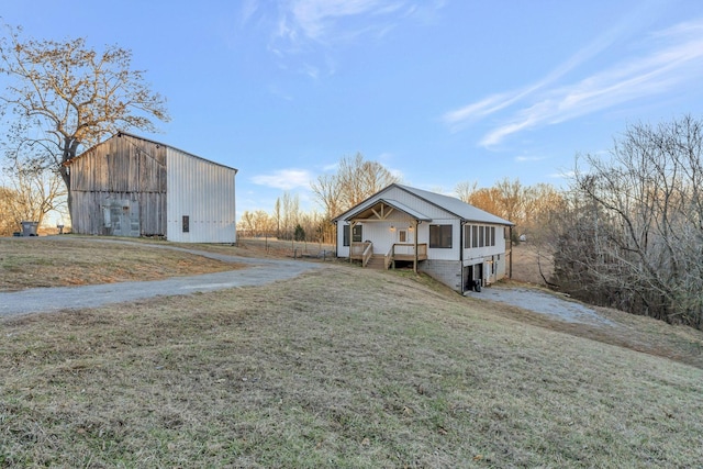 view of front of home with an outdoor structure, a front lawn, and a sunroom